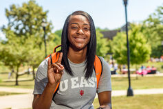 IU East student on campus showing the Red Wolf hand gesture.